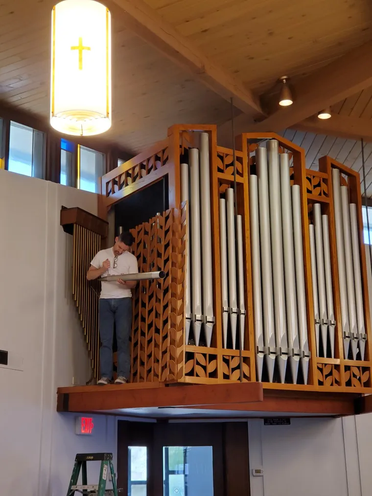 Installed pipe organ beside a stained glass window